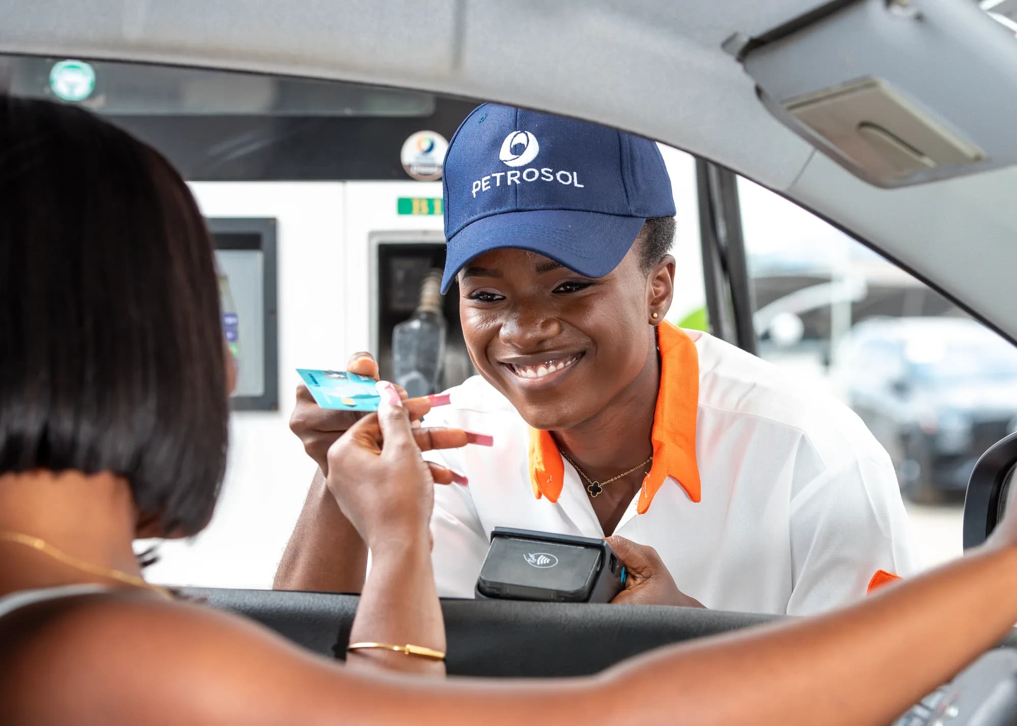 A PETROSOL forecourt attendant taking a card payment at a customer's car window