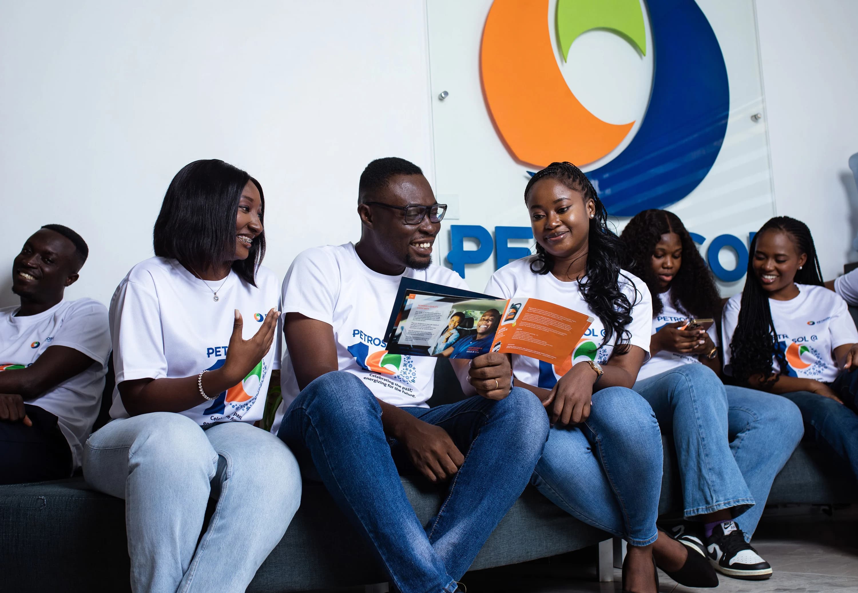 PETROSOL colleagues in branded team shirts reading a company brochure together at the head office